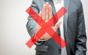 手のひらをこちらに向けて断るスーツの男性