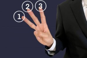3本の指を出すスーツの男性