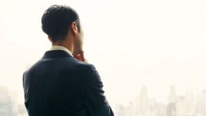 外を見て悩む男性の後ろ姿